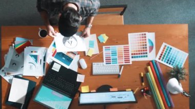 Akıllı iş adamının logo grafiği tasarlarken renk paletleri seçmesinin üst görünümü. Profesyonel iç mimar tasarımının hava görünümü ve renk paletleri kullanarak renk temasını seçin. Sempozyum.