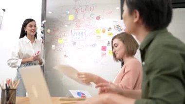 Genç ve güzel yatırımcı pazarlama stratejisi hakkında yorumlar yaparken çekici iş kadını da cam kurulun önünde renkli yapışkan notlar ve toplantı odasında zihin haritasıyla tavsiyeler dinliyor. Tertemiz..