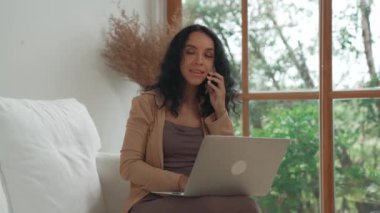 Telefonda konuşan Afro-Amerikalı bir kadın, internet üzerinde önemli bir iş için dizüstü bilgisayar kullanırken, aynı zamanda telesal yapıyor. Evde çalışan sekreter veya çevrimiçi içerik yazma.
