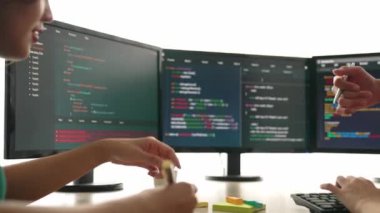 Yavaş çekim arkası yazılım geliştirici mühendisi bilgisayar programlama için birlikte çalışarak hata ayıklama kodunu çözüyor, ofiste monitörde karmaşık algoritmaları çözüyor. Filizlenen