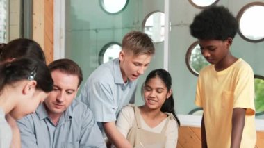 Akıllı robotlar sınıfta dizüstü bilgisayar ekranını işaret ederken, beyaz bir öğretmen yorum yapıyor ya da öğrencilere tavsiye veriyor. Öğretmen bilgisayar kullanırken çeşitli öğrencilerin ders verirken not alması. Öğretim