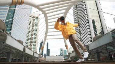 Asyalı hippi break dans çalışmasının düşük açılı kamerası ya da kulaklık takarken break dans performansı. Serbest dans, break dans, sokak dansı. Neşeli bir ruh hali. Açık hava sporu 2024. Yumuşak bir şekilde..