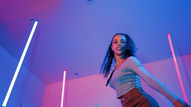 Latin dansçıların kameraya bakıp şehrin pop müziğiyle dans ettiği düşük açılı kamera. Profesyonel çekici hipster, mor veya neon ışıklı hip hop şarkısına geçiyor. Şık bir kumaş. Mutluluk.