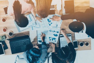 Modern ofisteki iş adamları ve iş kadınlarıyla grup toplantısındaki iş adamlarının en üst düzey görüşü, masada dizüstü bilgisayar, kahve ve belge ile. Kurumsal şirketler uds