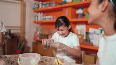 Çömlekçilik atölyesinde arkadaşıyla birlikte mutlu bir beyaz kız modellik kupası. Zeki Asyalı kız, arkadaşının yaratıcı aktiviteleri sırasında sanat dersine katılırken hamuru parçalıyor. Eğitim konsepti. Öğretim