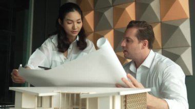 Profesyonel mimar mühendis takım tasarımı ve proje planı kullanarak ev hakkında tartışmalar. Proje yöneticisi, ev inşaatını mimari modeli masaya yerleştirilmiş mühendislere açıklıyor. Yönlendirici.