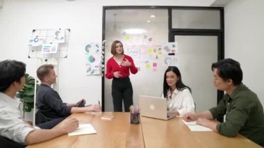 Genç liderin kapanışı, proje hakkında beyin fırtınası yapan meslektaşı ve proje yöneticisi tarafından çevrelenmiş zihin haritası ve renkli yapışkan notlar kullanılarak kendinden emin bir şekilde iş projesini sunuyor. Tertemiz..