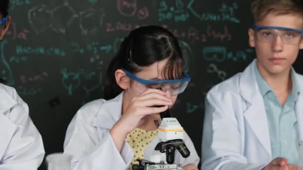 Симпатичная Девушка Смотрит Микроскопом Пока Студент Проводит Эксперимент Доске Теорией — стоковое видео