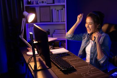 Sunucu kanalı Asyalı etkileyicisi canlı yayında konuşuyor. Sosyal medyada kulaklık takıyor, bilgisayar kaydı yapıyor, dinleyicileri selamlıyor ve Neon Modern Stüdyoları 'nda online olarak koçluk yapıyor. Taktik.