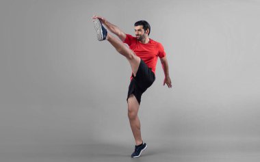 Vücut uzunluğunun tamamı atletik ve sporcu genç bir adamın kardiyo egzersizinde, izole edilmiş arka planda tekme pozisyonunda. Sağlıklı aktif ve vücut bakımı yaşam tarzı.