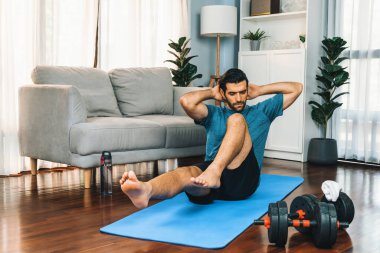Atletik ve sporcu adam, evde vücut egzersizi yaparken spor ve spor yaşam tarzına uyum sağlamak için spor minderinde çatırdıyor. Gaiety ev egzersizi antrenman konsepti.