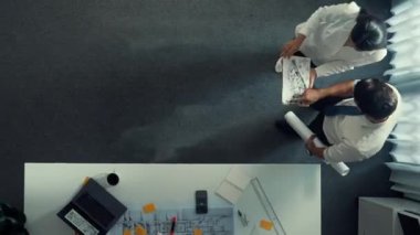 Mühendislik toplantısına katılırken ev tasarımına bakan zeki Kafkas proje yöneticisinin zaman aşımı. Mimar mühendis grubunun planlara bakarken birlikte çalıştığı hava görüntüsü. Hizalama.