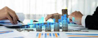 Dijital grafik göstergeli bozuk para yığını iş yatırımını ve ekonomik büyümeyi sembolize ediyor. Finansal hedefe ulaşmak ve kâr sağlamak için finansal planlama yapan bir iş adamı. Kurnaz.