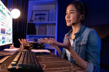 Sunucu kanalı Asyalı etkileyicisi, sosyal medyada kulaklık takarak iş grafikleri ekranında dinleyicileri selamlıyor ve Neon Modern Stüdyoları 'nda internet üzerinden koçluk yapıyor. Taktik.