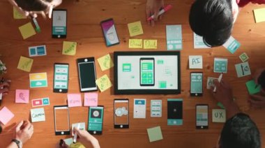 Ux ui tasarımını renkli yapışkan nota üzerine yazmak için birlikte çalışan geliştirici ekibinin üst görüşü. Tablet 'te kablo prototipi inceleyen ve yazılım tasarlayan bir grup programcı. Cemaat.