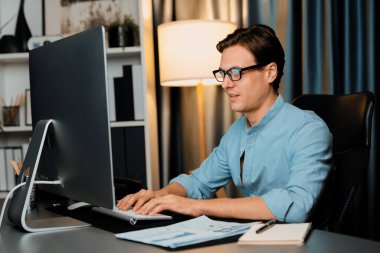 Akıllı iş adamı iş paragrafı dinamik pazarlama analizi planını analiz ediyor. Kağıt kağıtları ve bilgisayar monitörü raporlarını gece evdeki belge verileriyle karşılaştırmak için hazırlıyor. Bireysel.