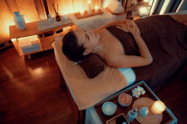 Beyaz kadın müşteri stres önleyici spa masajının keyfini çıkarıyor ve lüks otel ya da otelde sıcak mum ışığında güzellik teniyle eğleniyor. Sessiz.