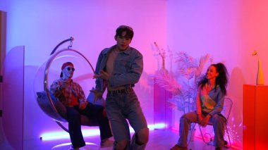 Çok kültürlü bir arkadaş kürsüde otururken Asyalı yetenekli bir dansçı modern müziğe geçiyor. Profesyonel dansçı, hipster takımı tezahürat yaparken ve desteklerken enerjik adımlar atıyor. Mutluluk.