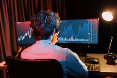 Dinamik döviz kurunu işaret eden borsa grafiğindeki ekranlarda geceleri modern neon ışığı ofisinde gerçek zamanlı genç yatırımcı finansal teknoloji verilerini analiz ediyor. Toplayıcı.