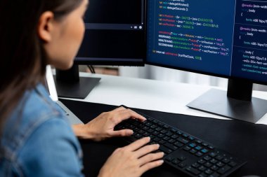 İnternet sitesi uygulamasının kodlama verileriyle birlikte online bilgi yazarak kot gömlek giyen genç Asyalı geliştirici. Güvenlik analizi ile çevrili iki ekran. Taktik.