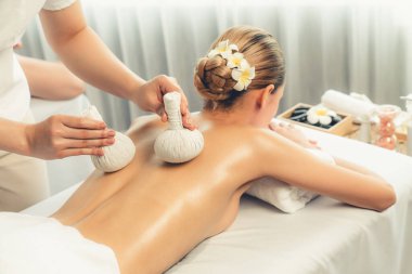 Sıcak bitkisel top spa masaj vücut tedavisi, masör kadın vücuduna nazikçe şifalı bitki torbası bastırıyor. Aromaterapi dinlenme sükuneti ve sükuneti kaplıca salonundaki atmosferi aydınlatıyor. Sessiz.