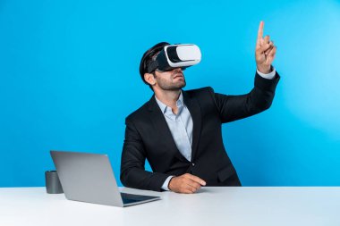 Bilgisayarla masada otururken ve VR gözlüğü takarken veri analizine bakan yetenekli bir iş adamı. Proje yöneticisi sanal gerçeklik sistemini kullanarak ya da metaevrende bağlantı kurarak çalışıyor. Sapma.