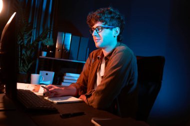 Genç işadamı, Neon Light Modern Ofis 'te yaratıcı bir başlangıç projesi için bilgisayara odaklanıyor. Düşünüyorum da, pazarlama ağı yaratıcıdan pazar kanalı tasarım konseptine çevrimiçi planlama. Toplayıcı.