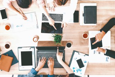 Modern ofisteki iş adamları ve iş kadınlarıyla grup toplantısındaki iş adamlarının en üst düzey görüşü, masada dizüstü bilgisayar, kahve ve belge ile. Kurumsal şirketler uds