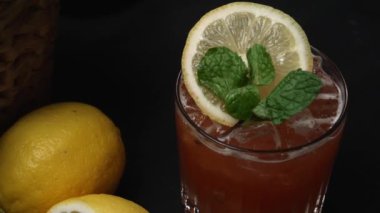 Makrografi, bir dilim limon ve taze naneyle süslenmiş Tekila Sunrise kokteyli, dramatik bir siyah arkaplan üzerine kurulmuş. Yakın çekim kokteylin canlı renklerini yakalar. Geliştirilebilir.
