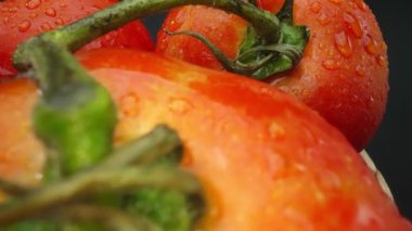 Makrografi, ahşap bir sepete yerleştirilmiş domatesler dramatik bir siyah arka plana karşı sergileniyor. Her yakın çekim domateslerin zengin renklerini ve dokularını yakalar. Geliştirilebilir.