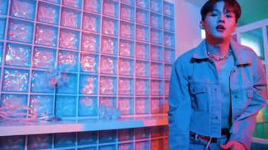 Çekici Asyalı sanatçı parlak neon ışıkta adım atıyor. Kameraya özgüvenle bakarken serbest stil müzikle dans eden yakışıklı break dans. Profesyonel hippi rahatla. Mutluluk.