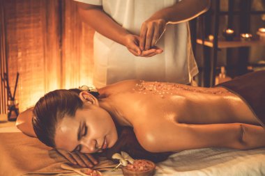 Lüks spa salonlarında sıcak mum ışığında cilt bakımı yaptıran kadın müşteri. Sağlık Spa vücut fırçasında tuz temizleme güzellik tedavisi. Sessiz.