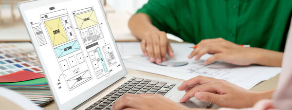 Cropped image of interior designer team discuss the material color while laptop displayed website wireframe designs for mobiles app and website. Creative design and business concept. Variegated.