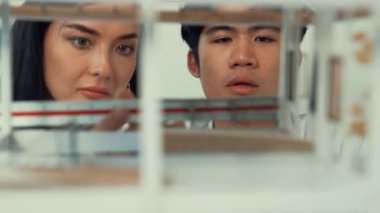 Ev modeli yapısını ölçmek için birlikte çalışan kooperatif mühendisi kapatın. Genç ve güzel mimar ev modelini ölçerken erkek mühendis performansını destekliyor. Tertemiz..