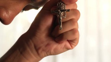 Hristiyan katolik takipçilerle dinsel bağlılık ve maneviyat duygusu doludur. Ağır çekimde Hristiyan, Tanrı 'ya ibadet etmek için dua ederken kutsal haçı tutuyor. Filizlenen