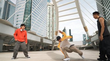 Asyalı hippi şehir merkezinde dans ederken profesyonel mutlu sokak dansçıları grubu neşelenin. Düşük açılı kameralı insanlarla çevrili. Break dans konsepti. Açık hava sporu 2024. Yumuşak bir şekilde..