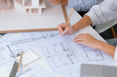 Profesyonel erkek mühendis ev modelini cetvel kullanarak ölçerken güzel bir iş arkadaşı da plan üzerinde yazarak birlikte çalışıyor. Yaratıcı tasarım ve takım çalışması. - Yakın çekim. Tertemiz..