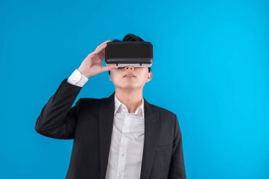 Sanal gerçeklikteki yenilik teknolojisi reklamlarını analiz ederek iş dünyası raporuna tam anlamıyla bağlanan gülümseyen Asyalı işadamı. Entrika.