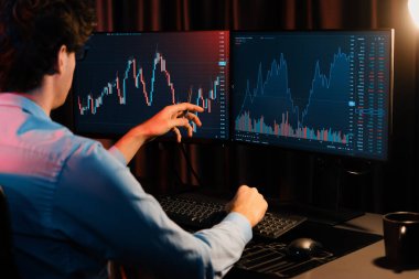 Piyasa stok grafik veri planlama üzerine çalışan genç tüccar Neon Modern Ofis 'te arka taraf görüşü ile gerçek zamanlı izleme yapıyor. Dinamik para bozdurma oranını analiz etme kavramı. Toplayıcı.