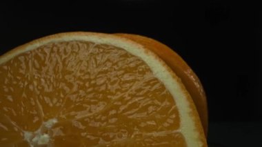 Portakal diliminin bir makrografi görüntüsü, parlak, izole edilmiş bir arkaplan üzerine yerleştirilmiş, narenciye cazibesinin görsel bir başyapıtı olarak gözler önüne seriliyor. Siyah arkaplanlı bir dilim portakal. Geliştirilebilir.