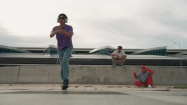 Bir grup Asyalı break dansçı, çok kültürlü arkadaş desteği ve hareketli hip hop müziğiyle sokak dansı yaptılar. Çekici yakışıklı hippi sokak dansında break dansçı. Açık hava sporu 2024. Yumuşak bir şekilde..