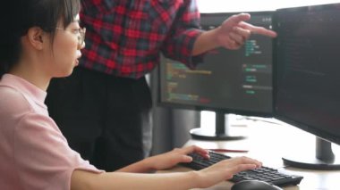 Yavaş çekimde geri uç veya yazılım geliştirici yöneticisi ekibini monitörde hata ayıklama ve karmaşık kod algoritmalarını çözmede yeni uygulama programı geliştirmede denetliyor. Filizlenen