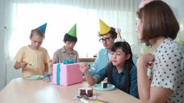 Çekici aile, modern mutfakta masaya konmuş renkli balonla süslenmiş bir şekilde konuşurken kızının doğum gününü kutluyor. Mutlu Asyalı kız gülümseyen ailesiyle pasta yiyor. Pedagoji.