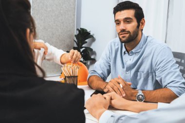 Mimari proje üzerinde birlikte çalışan çeşitli inşaat mühendisi ve müvekkil grupları, inşaat planını gözden geçirip toplantı masasında plan oluşturuyorlar. Tedbirli