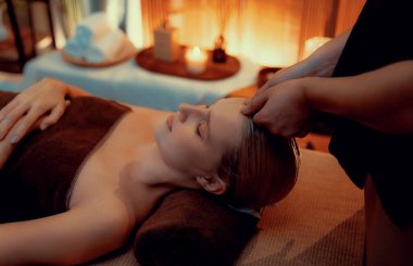 Beyaz kadın stres önleyici kafa masajı yapmaktan ve lüks otel veya otelde sıcak mum ışığında yüz güzelliği eğlencesi yapmaktan zevk alıyor. Sessiz.