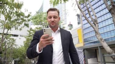 Düşük açılı kamera görüntüsü iş adamının telefonuna bakarken pazarlama ekibini arayıp Green City 'deki finansal plan hakkında fikir alışverişinde bulunması. Yönetici, iş arkadaşıyla telefonla konuşuyor. Urbane.