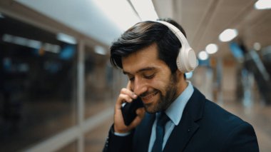 Akıllı bir iş adamı tren istasyonunda kulaklık takarken telefon eder. Profesyonel yönetici, tren ya da metro beklerken pazarlama stratejisi hakkında meslektaşıyla konuşuyor. Sevinçli..