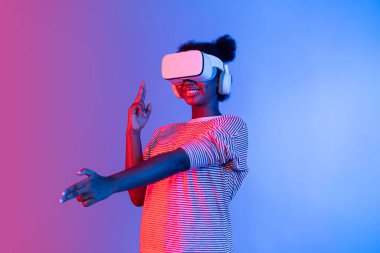 VR kullanan Afrikalı bir oyuncuyu avlamak, meta-evrende silah ateşleme oyunu oynamak, mavi neon ışığını izole etmek, zafer hayvanı avlamak, fütüristik teknoloji hologramı sanal gerçekliği. Entrika.