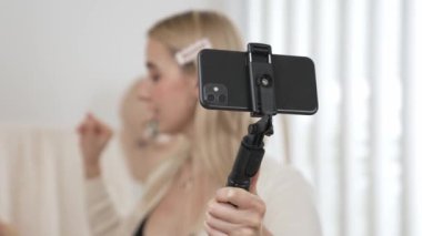 Genç sosyal medyum kadın selfie çubuğuyla moda videosu yapıyor. Blogcu kameraya gülümserken çevrimiçi kıyafetleri izleyicilere ya da takipçilere vlog sattırıyor. Blithe