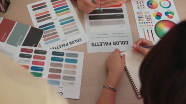 Üst görünüm yavaş çekim eli, grafik tasarımı için çalışan iki tasarımcının ya da tasarımcıdan yaratıcı kromatik konsültasyonda renk uygulaması arayan istemcinin masasının üzerinde. Değiştirilmiş